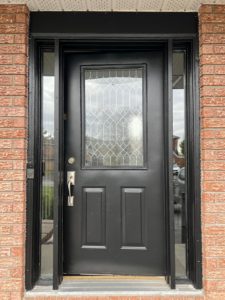 Black door with two sidelights, featuring glass at the top and wood at the bottom, creating a modern and stylish entrance.