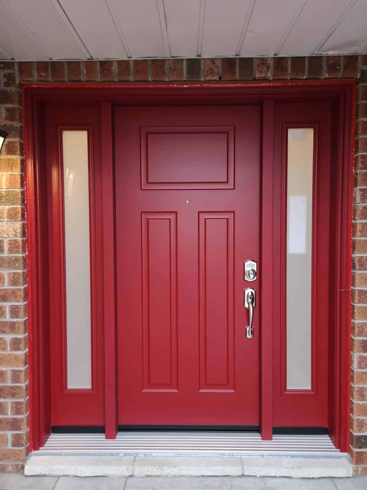 Red door with two sidelights, adding a vibrant touch to home design