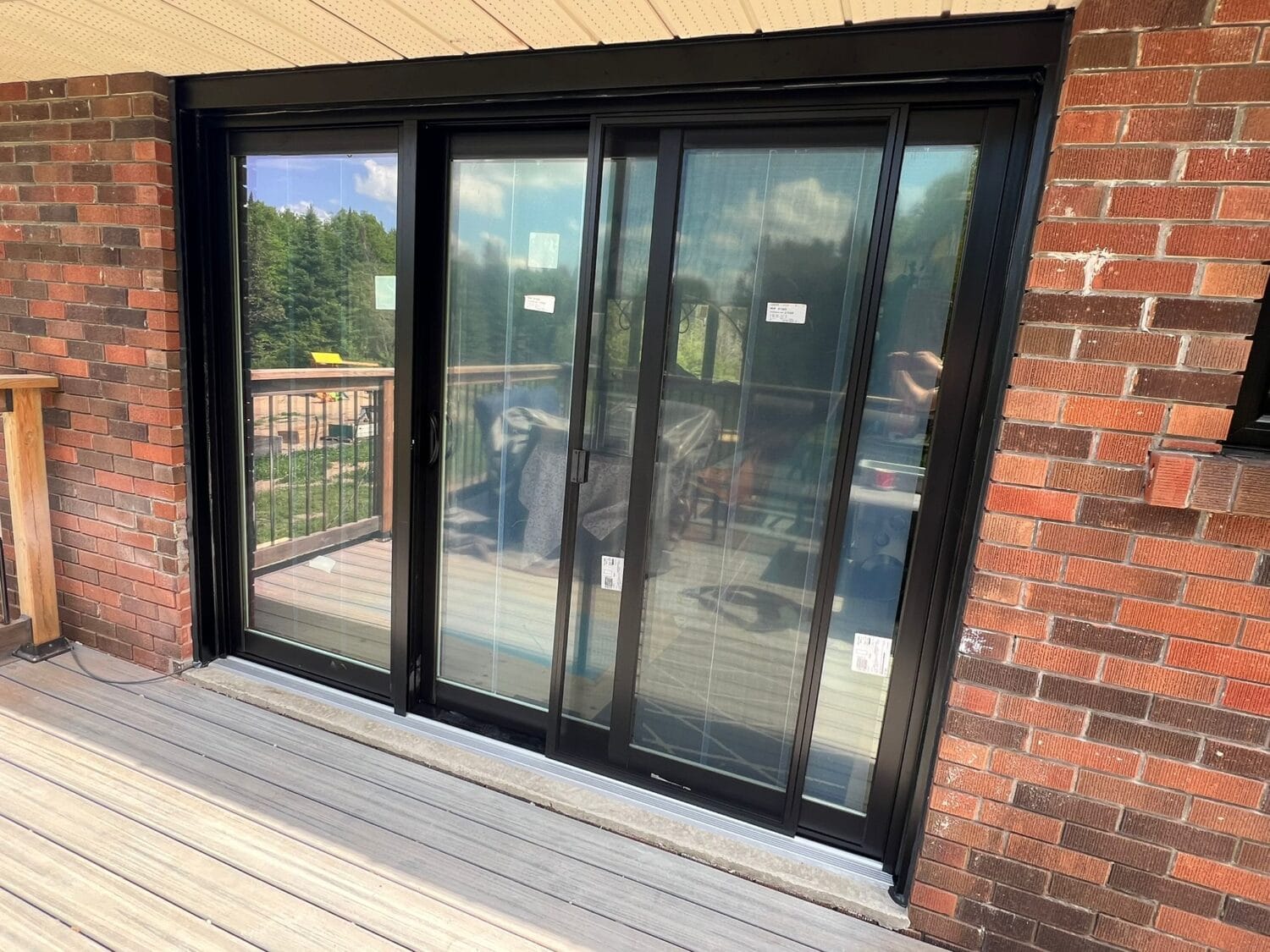 Sliding glass doors leading to a patio, framed in black, with sunlight filtering through.